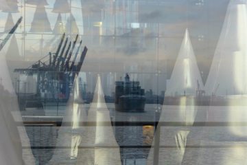 Hamburg, 2015. Stilisierte Weihnachts-bäume glänzen im Innern. Außen spiegelt das Fenster Hafen, Schiff und Elbe.